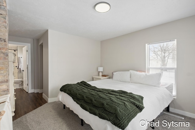 bedroom featuring ensuite bath, dark hardwood / wood-style floors, and a textured ceiling