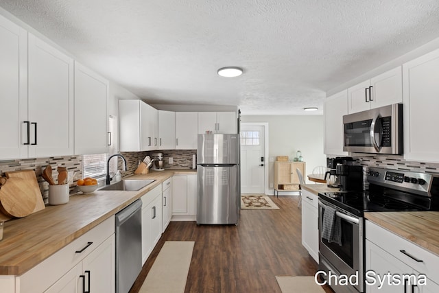 kitchen with stainless steel appliances, sink, white cabinets, and wood counters