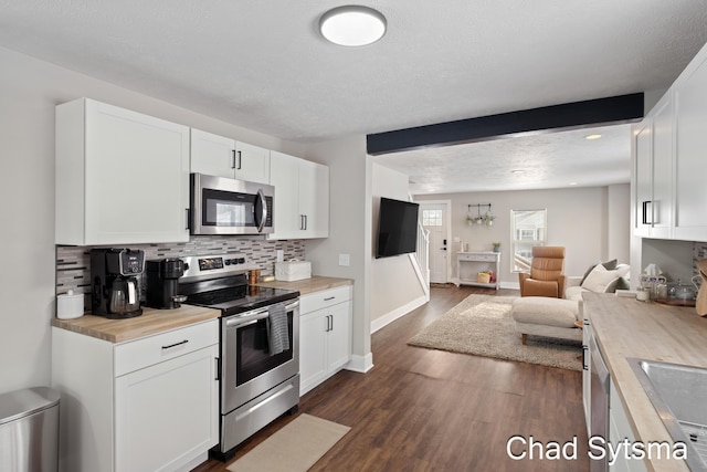 kitchen featuring white cabinetry, stainless steel appliances, and butcher block countertops