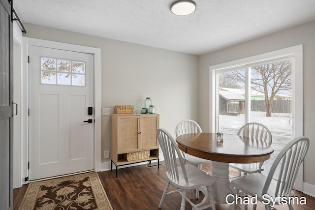 dining area with dark hardwood / wood-style flooring, a barn door, and a textured ceiling