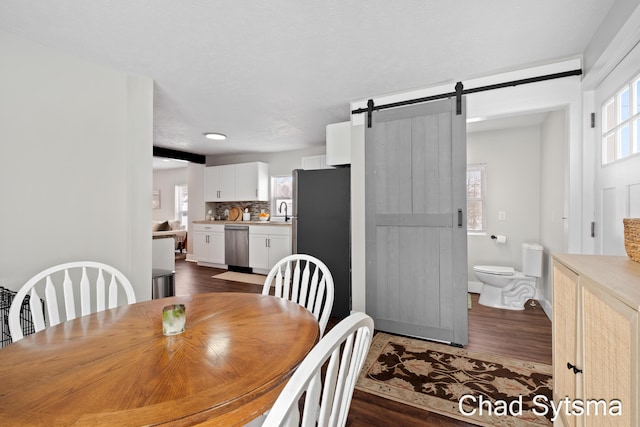 dining room featuring a barn door, a healthy amount of sunlight, sink, and dark hardwood / wood-style flooring