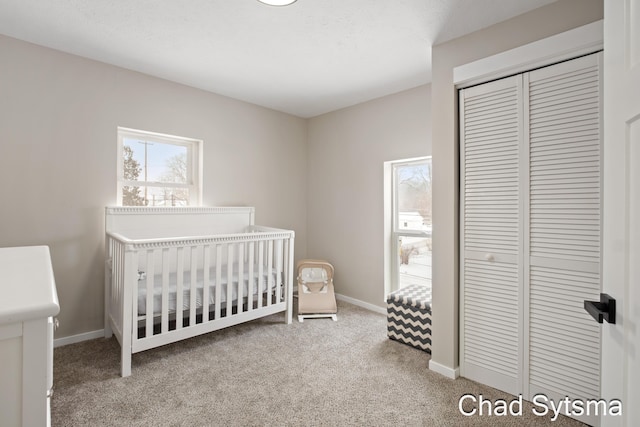 bedroom with a crib, carpet flooring, and a closet