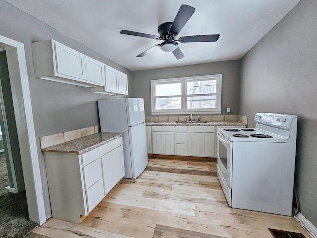 kitchen with sink, white cabinets, white appliances, and light hardwood / wood-style flooring