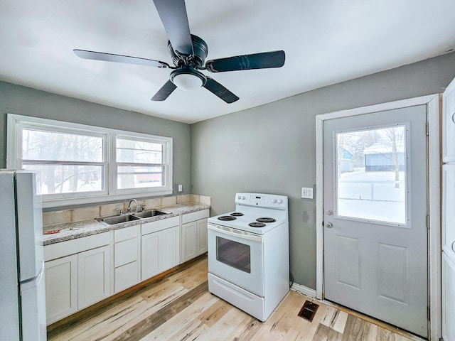 kitchen with sink, white cabinetry, light hardwood / wood-style flooring, ceiling fan, and white appliances