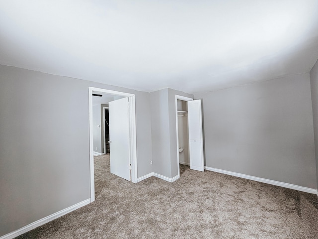 unfurnished bedroom with light colored carpet and a closet