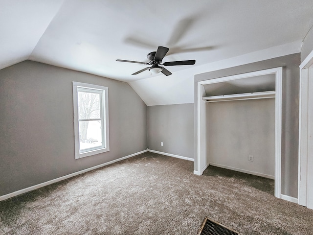 additional living space with dark colored carpet, lofted ceiling, and ceiling fan