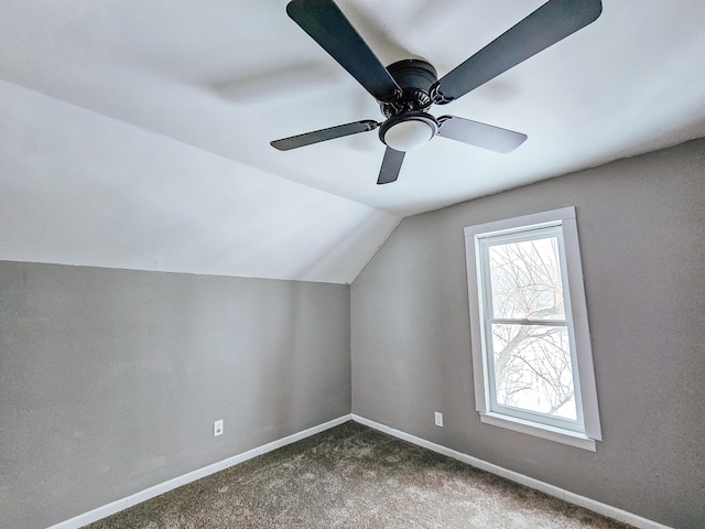 additional living space featuring dark colored carpet, vaulted ceiling, and ceiling fan