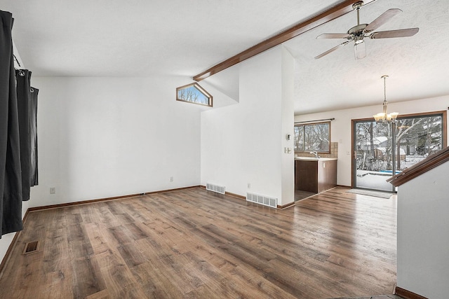 unfurnished living room with ceiling fan with notable chandelier, vaulted ceiling with beams, sink, and dark hardwood / wood-style floors