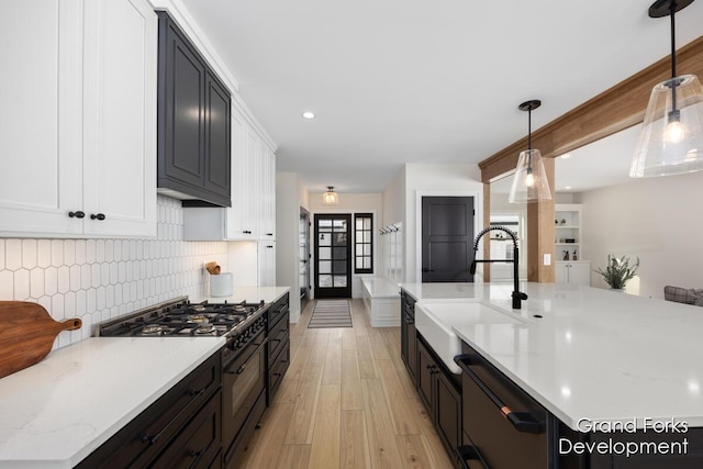 kitchen with decorative light fixtures, dishwasher, sink, double oven range, and light stone counters