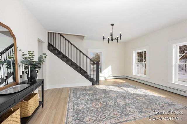 entrance foyer featuring a baseboard heating unit, a notable chandelier, and light hardwood / wood-style floors