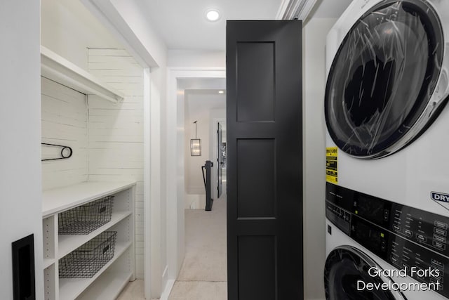 clothes washing area with stacked washer and clothes dryer