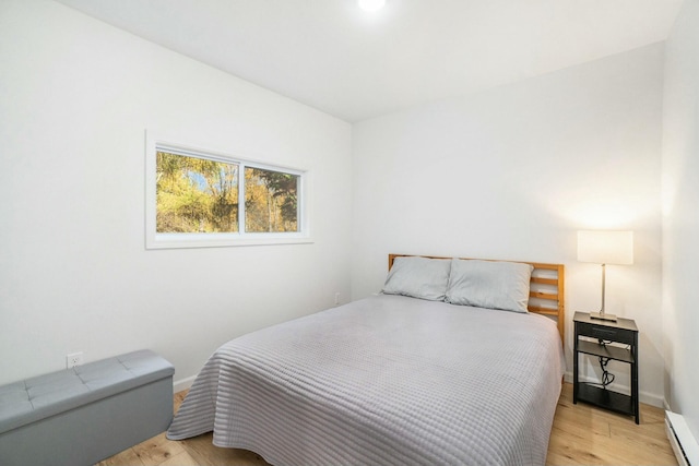 bedroom with baseboard heating and light hardwood / wood-style floors