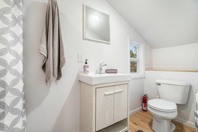 bathroom with hardwood / wood-style flooring, vanity, toilet, and vaulted ceiling