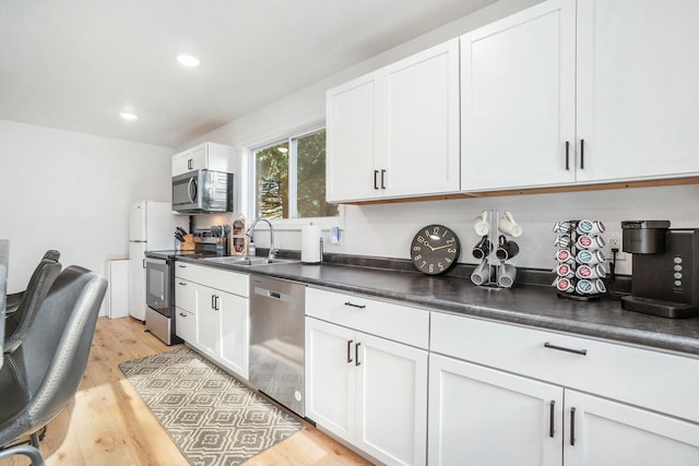 kitchen featuring stainless steel appliances, white cabinetry, sink, and light hardwood / wood-style flooring