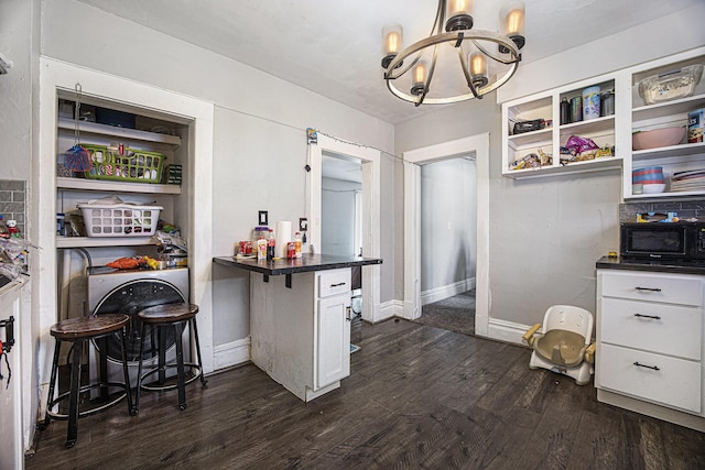 kitchen featuring hanging light fixtures, dark wood-type flooring, a breakfast bar, and white cabinets