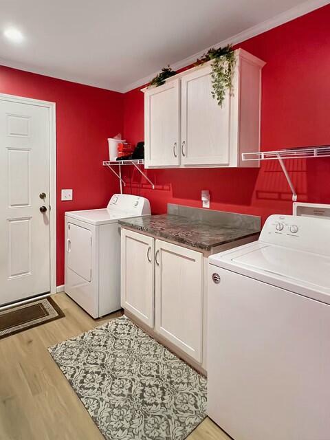 laundry room featuring washer and dryer, cabinets, crown molding, and light wood-type flooring