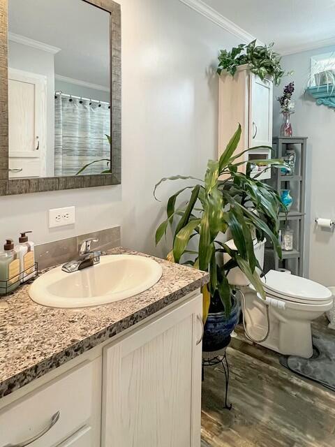 bathroom with hardwood / wood-style floors, toilet, vanity, and ornamental molding