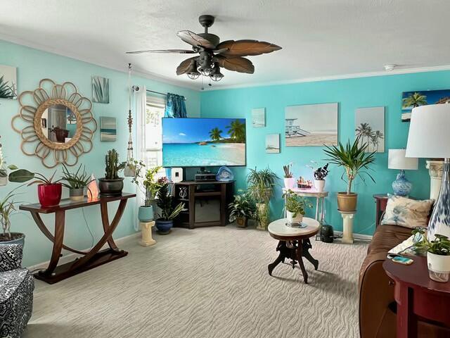 sitting room featuring ceiling fan, carpet flooring, and crown molding