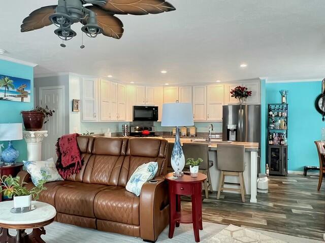 living room featuring ornamental molding, ceiling fan, and hardwood / wood-style floors