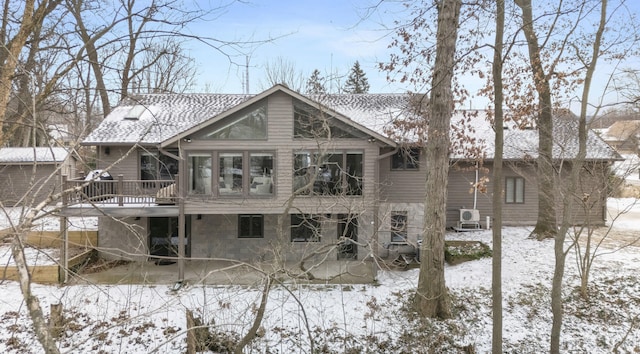 snow covered property with roof with shingles and a wooden deck