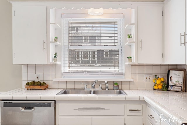 kitchen with sink, dishwasher, tasteful backsplash, tile counters, and white cabinets