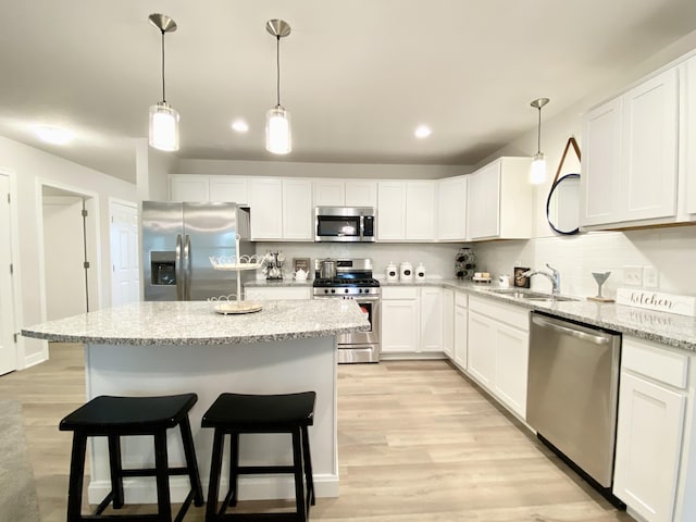 kitchen featuring pendant lighting, sink, white cabinets, and appliances with stainless steel finishes