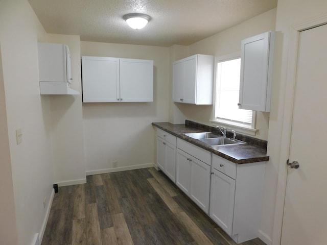 kitchen featuring white cabinetry, sink, dark wood-type flooring, and a textured ceiling