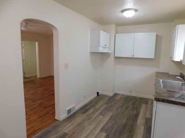 clothes washing area featuring sink, a textured ceiling, and dark hardwood / wood-style flooring