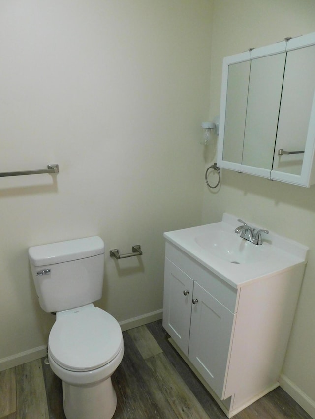 bathroom with wood-type flooring, vanity, and toilet