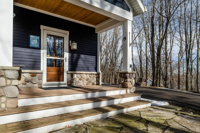 view of exterior entry with stone siding and covered porch