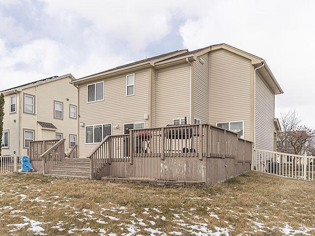 snow covered rear of property with a wooden deck