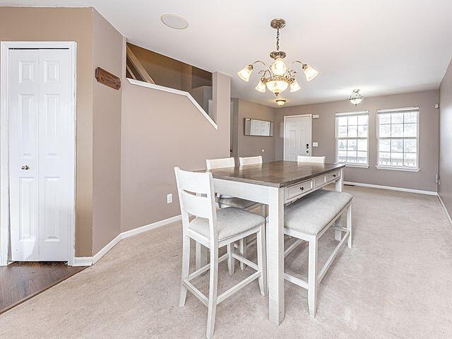 carpeted dining space with an inviting chandelier