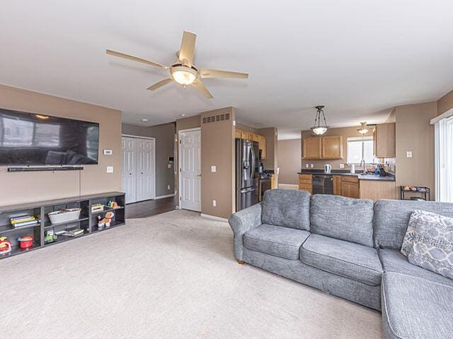 carpeted living room with sink and ceiling fan