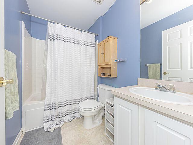 full bathroom featuring shower / bath combination with curtain, vanity, and toilet