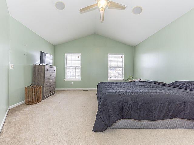 bedroom featuring ceiling fan, lofted ceiling, and light carpet