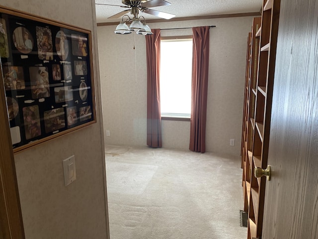 corridor with light carpet, a healthy amount of sunlight, and a textured ceiling