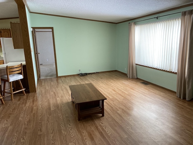 unfurnished living room with ornamental molding, hardwood / wood-style floors, and a textured ceiling