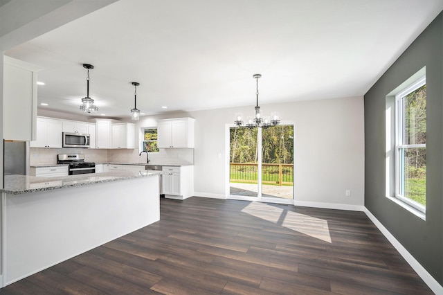 kitchen with appliances with stainless steel finishes, white cabinetry, light stone counters, tasteful backsplash, and a wealth of natural light