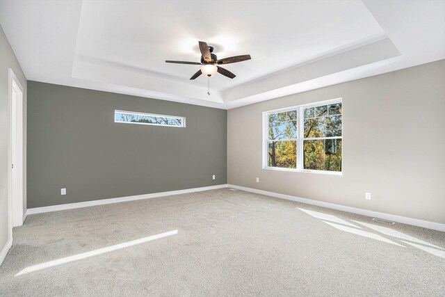 carpeted empty room featuring a raised ceiling and ceiling fan