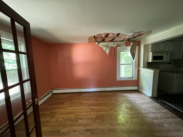 unfurnished dining area with dark wood-type flooring and a baseboard radiator