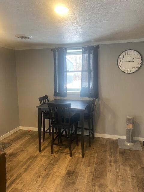 dining room with wood-type flooring and a textured ceiling