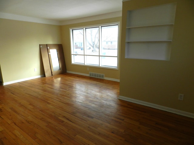 spare room with dark hardwood / wood-style flooring and built in shelves