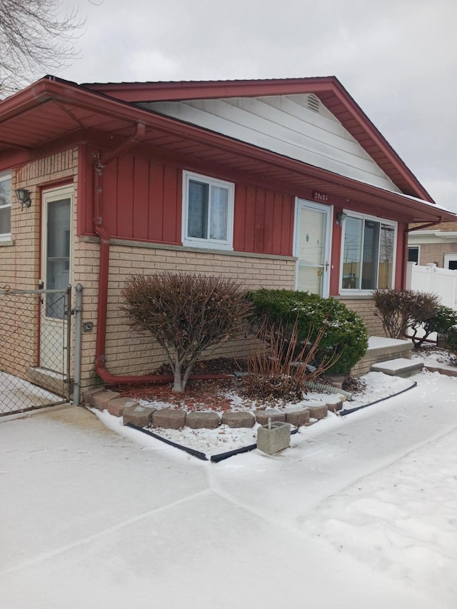 view of front facade with brick siding, board and batten siding, and fence