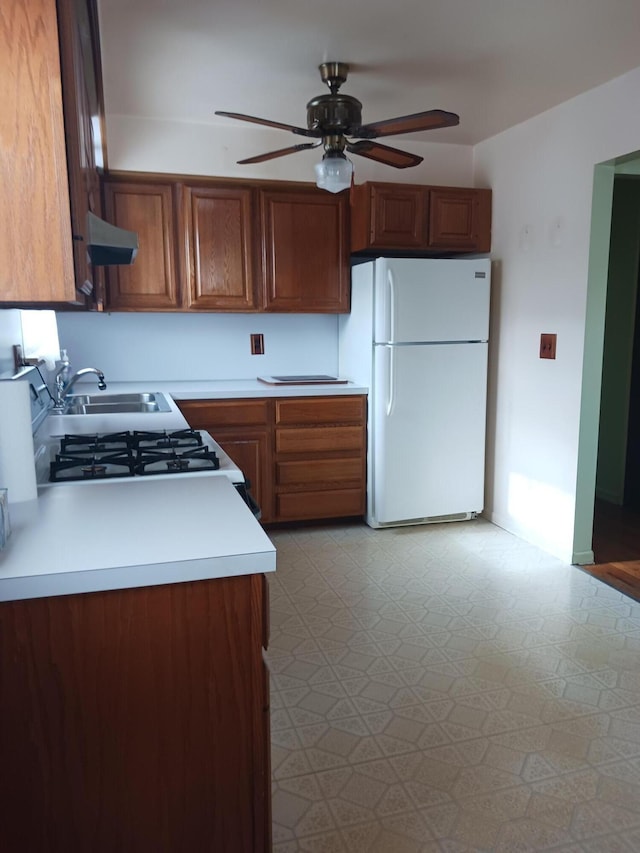 kitchen featuring white appliances, ceiling fan, extractor fan, light countertops, and a sink