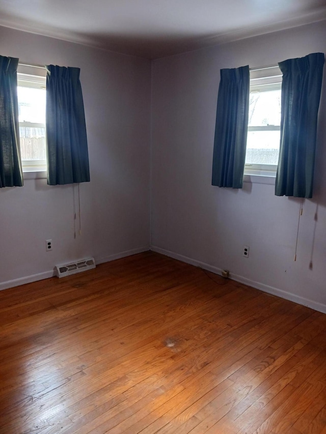 empty room featuring baseboards, plenty of natural light, visible vents, and light wood-style floors