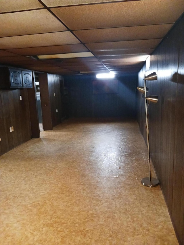 finished basement with wooden walls and a drop ceiling