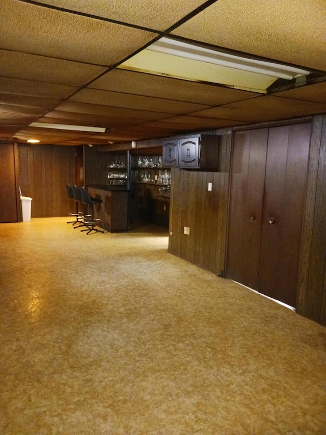 finished basement featuring a dry bar and wood walls