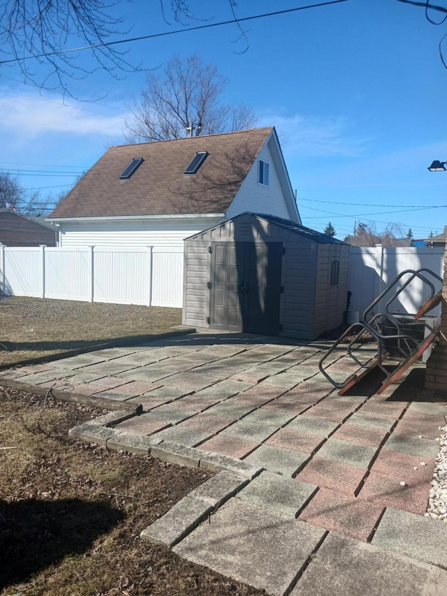 view of property exterior featuring a shed, roof with shingles, a fenced backyard, and an outdoor structure