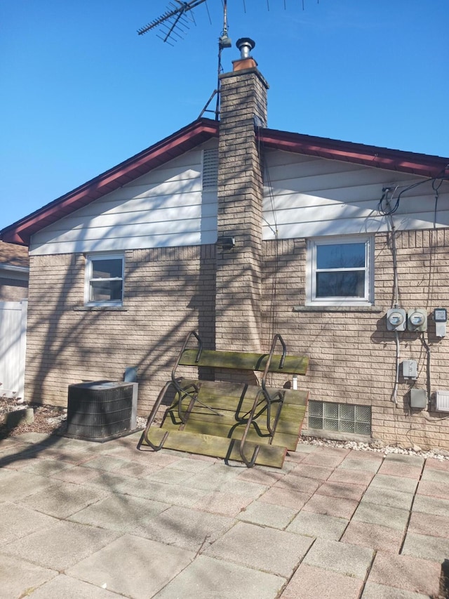 view of home's exterior featuring brick siding, a patio, and central air condition unit