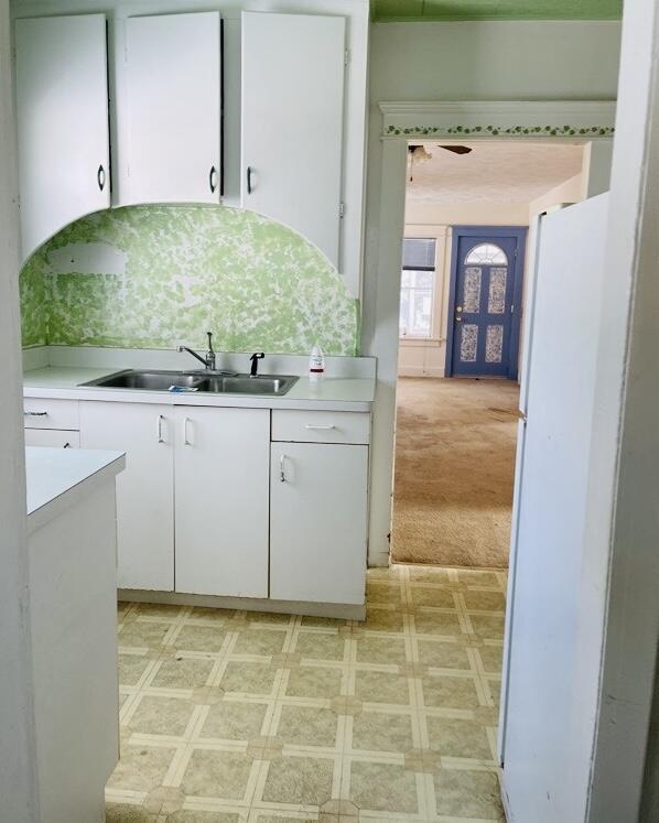 kitchen with sink, light colored carpet, white cabinets, and white fridge